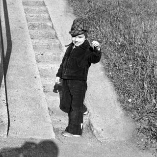 Young child climbing stairs outdoors in vintage attire.