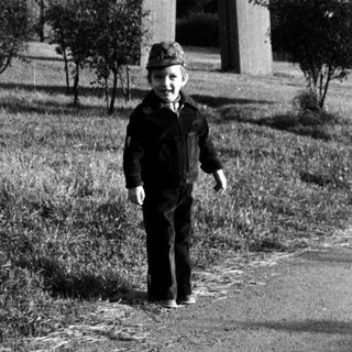 Boy standing alone near highway overpass.