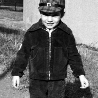 Young child walking outdoors with a small dog.