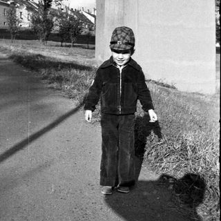 Young child walking outdoors with a small dog.