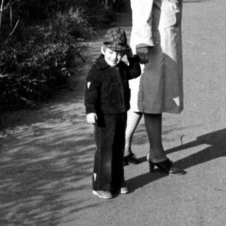 Two people walking on a wet roadside path.