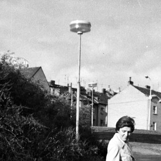 Two people walking on a wet roadside path.