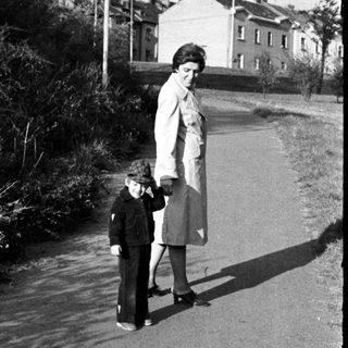 Two people walking on a wet roadside path.