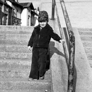 Child wearing uniform descends outdoor stone stairs.