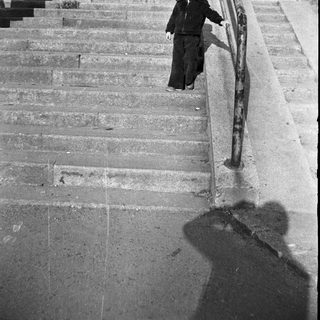 Child wearing uniform descends outdoor stone stairs.