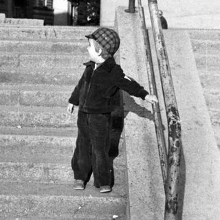 Child descending stairs with adult standing nearby.