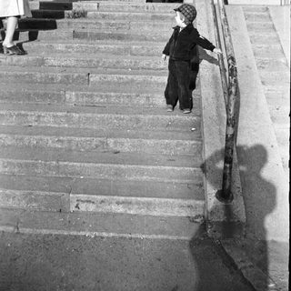 Child descending stairs with adult standing nearby.