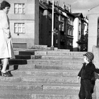 Child descending stairs with adult standing nearby.