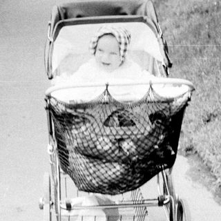 Baby in vintage pram on quiet pathway.