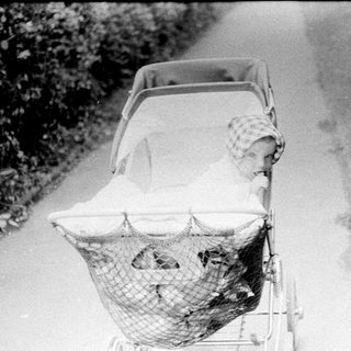 Baby in vintage pram on dirt road.
