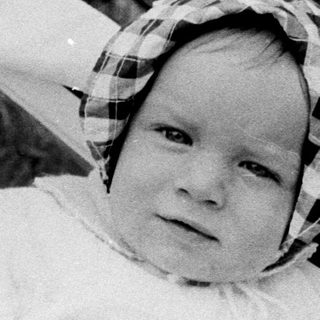Two babies in a bathtub with adult hands.