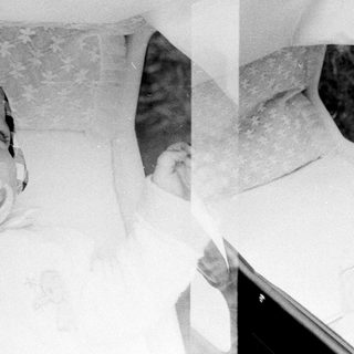 Two babies in a bathtub with adult hands.
