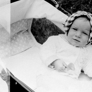 Two babies in a bathtub with adult hands.