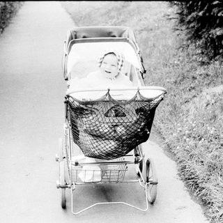 Baby in vintage pram on paved path.