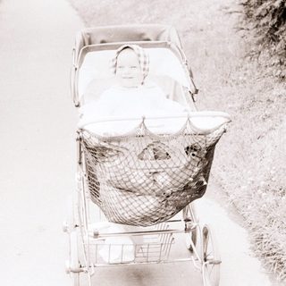 Baby stroller pushed along a rural path.
