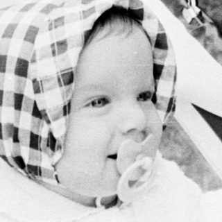 Baby in vintage pram with checkered hat.