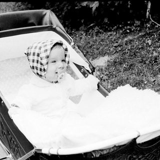 Baby in vintage pram with checkered hat.