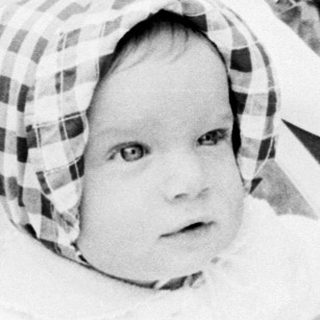 Baby in vintage pram with checkered hat.