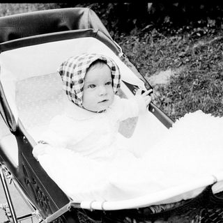 Baby in vintage pram with checkered hat.