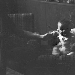 Child brushing teeth indoors by window.