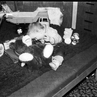 Baby playing with stuffed toys on bed.