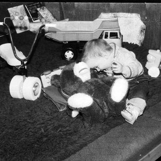 Baby playing with stuffed toys on bed.