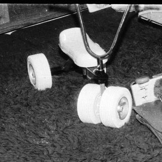 Toddler with a large teddy bear and toy tricycle on a shag rug