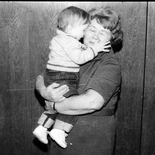A woman tenderly hugging a baby indoors.