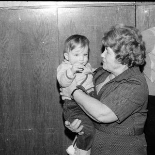 A woman holding a young child indoors.
