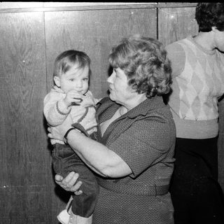 A woman holding a young child indoors.