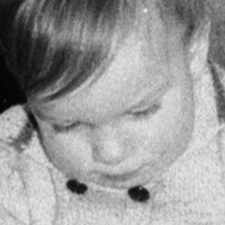 Child playing with toy airplane near decorated Christmas tree.