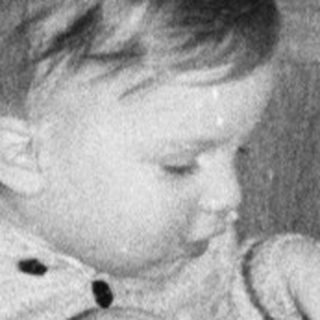 Young child playing with toys near decorated Christmas tree.
