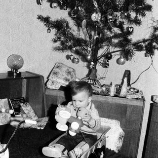 Child playing with toys near decorated Christmas tree.