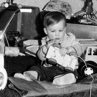 Baby playing with toy near decorated Christmas tree.