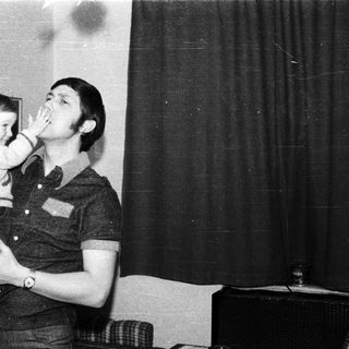 Man playfully kissing a young child indoors.