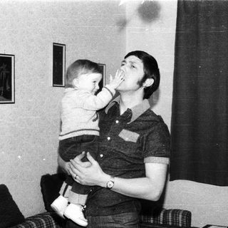 Man playfully kissing a young child indoors.