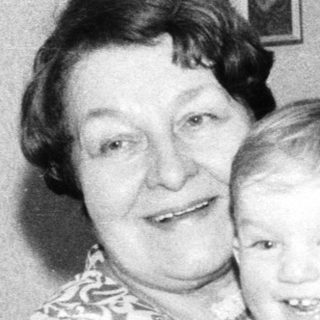 A woman holding a smiling young child indoors.