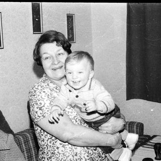 A woman holding a smiling young child indoors.