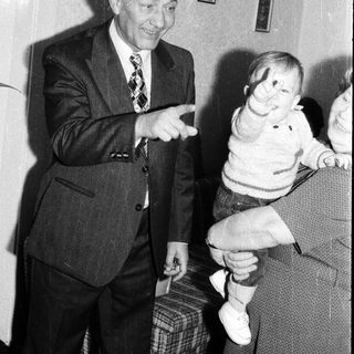 Elderly man playfully interacting with a young child indoors.