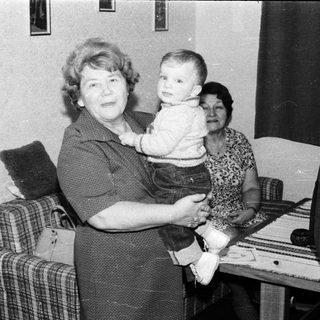 Family portrait with grandmother holding young child indoors.
