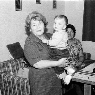 Family portrait with grandmother holding young child indoors.