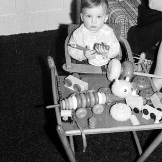 Young child in high chair playing with toy food.