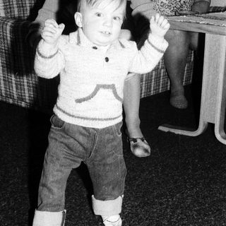 Young child dancing indoors with arms raised.