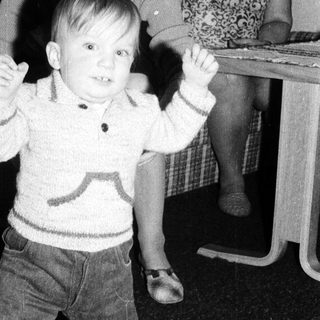 Young child dancing indoors with arms raised.