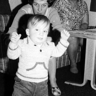 Young child dancing indoors with arms raised.