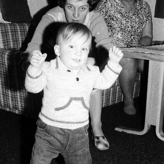 Young child dancing indoors with arms raised.