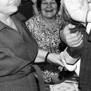 Joyful family moment with elderly couple holding baby indoors.