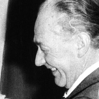 A man kisses a young child on the head while a woman watches.