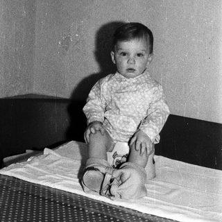 Young child sitting on bed.