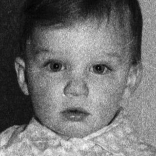 Young child sitting on bed.